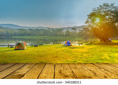 Camping and tent near lake in sunrise with empty wood floor