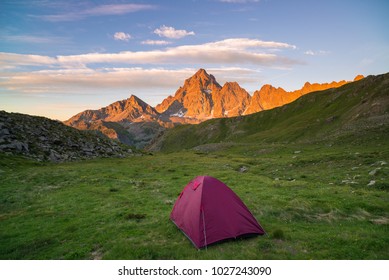 Camping with tent on the Alps.Snowcapped mountain range and scenic colorful sky at sunset. Adventure and exploration, conquering adversity. - Shutterstock ID 1027243090
