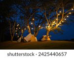 camping tent on grass courtyard and warm night light under dark blue sky. Family vacation picnic on holiday relax