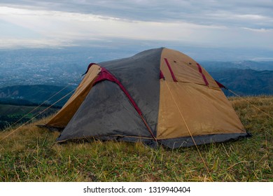 Camping Tent With The Opened Doorway And Raindrops On Its Surface Under Dramatic Overcast Sky Full Of Heavy Clouds. Hiking Tent After The Rain With Water Drops.