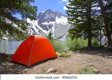 Camping tent in the Rocky Mountains with lake and snow capped peaks