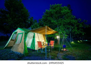 Camping tents at night, vintage cabin tents,  Antique lanterns, retro chairs, and outdoor coffee-making facilities on wooden tables in a forest - Powered by Shutterstock