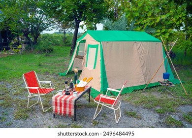 Camping tents at night, vintage cabin tents,  Antique lanterns, retro chairs, and outdoor coffee-making facilities on wooden tables in a forest - Powered by Shutterstock