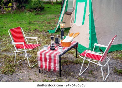 Camping tents at night, vintage cabin tents,  Antique lanterns, retro chairs, and outdoor coffee-making facilities on wooden tables in a forest - Powered by Shutterstock