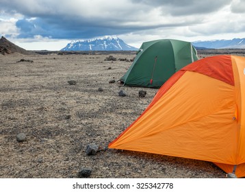Camping tents on a rocky campsite in Iceland with Herdubreid in background