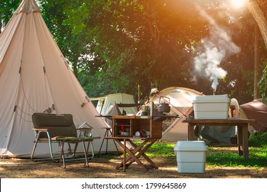 Camping Tents with Outdoor Camp Kitchenware Equipment and Vintage wood Table on Grass Field in Campground area at Forest, Summer Picnic Traveling Lifestyle in Nature Vacation - Powered by Shutterstock