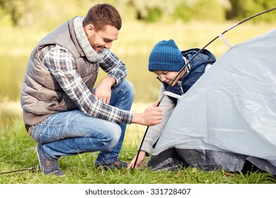 Camping, Tourism, Hike, Family And People Concept - Happy Father And Son Setting Up Tent Outdoors