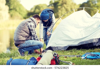 Camping, Tourism, Hike, Family And People Concept - Happy Father And Son Setting Up Tent Outdoors