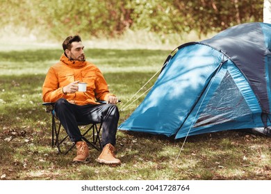 Camping, Tourism And Travel Concept - Happy Man Drinking Tea At Tent Camp