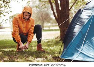 camping, tourism and travel concept - man setting up tent outdoors