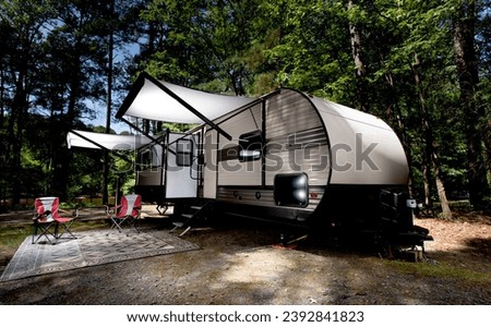 Campsite in the middle of the day with a camper trailer's awnings out