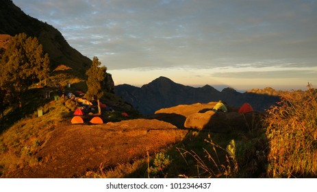 Campsite On The Volcano Edge. Sunrise On The Edge Of Rinjani. Trekking Image From The South East Asia. Adventure Holidays In Asia. Tents In The Early Sun.