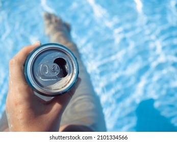 Can of beer and a cute woman on the background of the swim pool. Top view, close-up. Vacation and travel concept. Moments of celebration