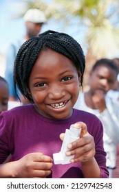 I Can Breathe Easy Now. Portrait Of A Little Girl Holding An Asthma Inhaler At A Community Outreach Event.