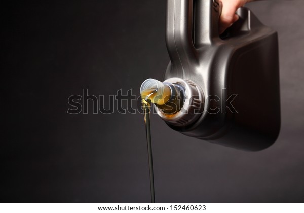 Can\
with car engine oil pouring in front black\
background