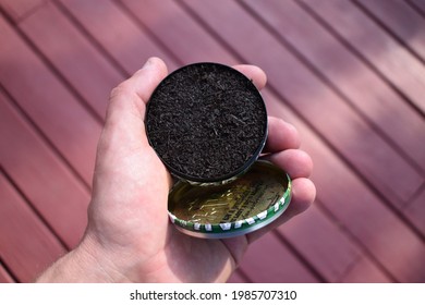 Can of chewing tobacco held in a hand