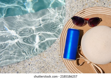 Can Of Cold Drink, Straw Hat And Sunglasses On The Edge Of The Hotel Pool. View From Above.