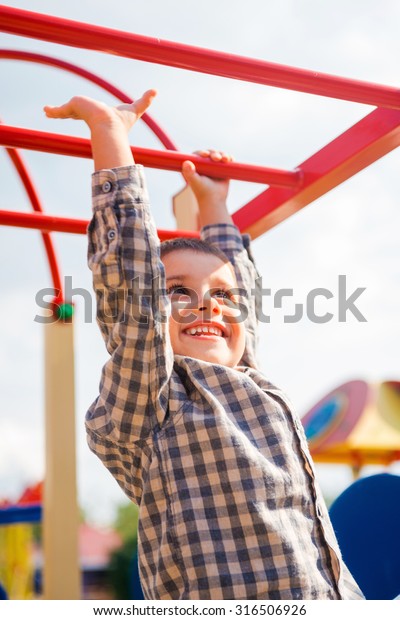I can do it! Playful little boy
expressing positivity while having fun on jungle
gym