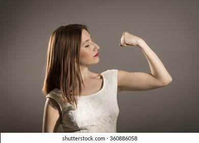 I can handle any obstacle. Young woman shows her muscles, strength and power concept, studio shoot on gray. "I can do anything!" 