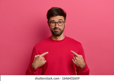 I can handle it. Assertive determined man with beard points at himeself, feels proud and brags about own achievements, proposes own help, wears red sweater, eyewear, stands against pink background - Shutterstock ID 1646432659