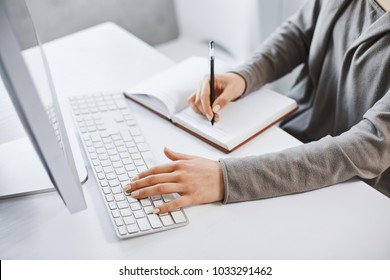 I can handle multi tasks. Cropped shot successful girl typing on keyboard and making notes while looking at computer screen and studying new business graphic. There is no time for rest - Powered by Shutterstock