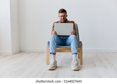 I Can Not Believe It Concept. Shocked Scared Young Man With Laptop On Knees Made Critical Mistake Hates Operation Problems Computer Breakdown Opening Mouth. Remote Job Work From Home. Front View