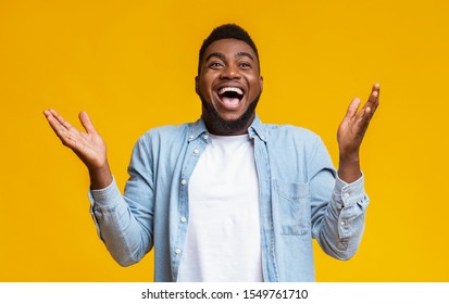 I Can Not Believe. Portrait Of Joyful African American Man Raising Hands In The Air With Excitement And Looking At Camera, Yellow Studio Background.