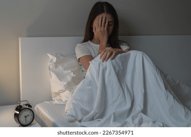 Can not sleep, depressed asian young woman, girl suffering sitting in bed from insomnia problem, awake at night, covering face with hand because of disturbed loud noise, unable sleep. Restless people.
