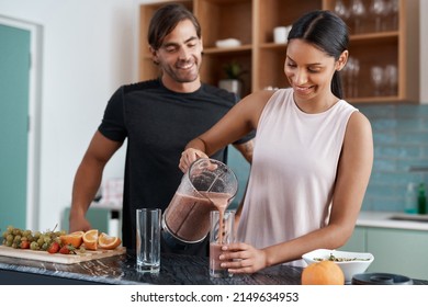 Can I pour you a glass. Cropped shot of an affectionate young couple making smoothies in their kitchen at home. - Powered by Shutterstock