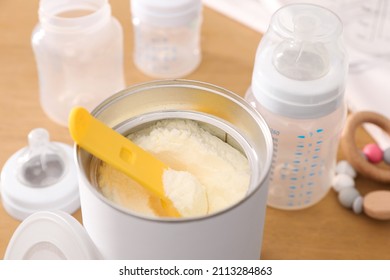 Can of powdered infant formula with scoop on table, closeup. Baby milk