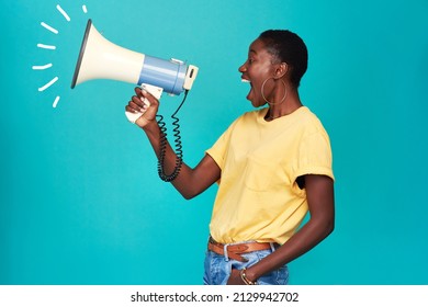 It Can Take One Voice To Change The World. Studio Shot Of A Young Woman Using A Megaphone Against A Turquoise Background.