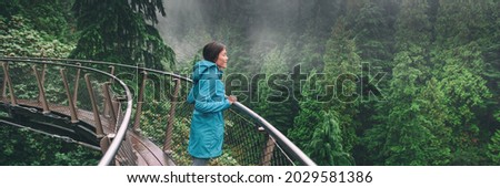 Canada Autumn travel destination in British Columbia. Asian tourist woman walking in famous attraction Capilano Suspension Bridge Park in North Vancouver. Canadian vacation banner.