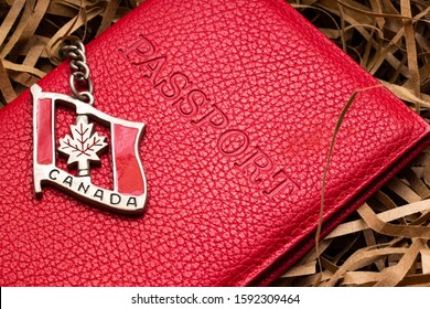 Canada Citizenship Passport Concept. Steel Flag Of Canada With Chain Lying On A Red Passport Cover Background. The Concept Of Migration, Work And Travel.