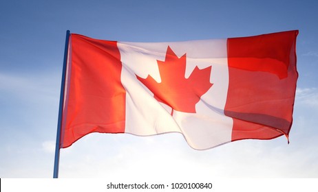 Canada Flag On Clear Blue Sky With Sun