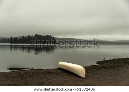 Canada Ontario Lake two rivers grey morning dark atmosphere Canoe Canoes parked beach water in Algonquin National Park
