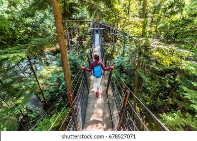 Canada travel tourist woman walking in famous attraction Capilano Suspension Bridge in North Vancouver, British Columbia, canadian vacation destination for tourism.