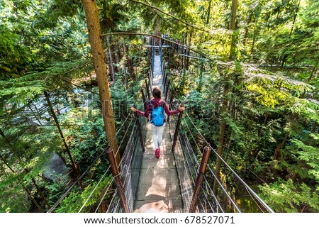 Canada travel tourist woman walking in famous attraction Capilano Suspension Bridge in North Vancouver, British Columbia, canadian vacation destination for tourism.