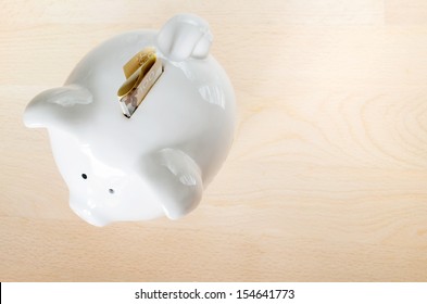 Canadian  $100 Dollar Bill, Folded, Sticking Out Of Small White Piggy Bank On Wooden Cut Board