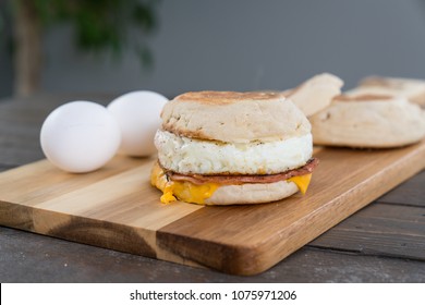 Canadian Bacon, Egg And Cheese Breakfast Sandwich With English Muffin On Cutting Board