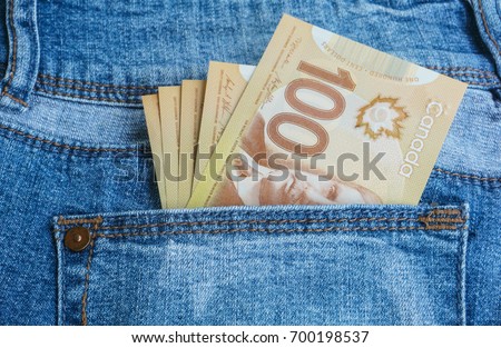 Canadian banknotes are in the back pocket of blue jeans.