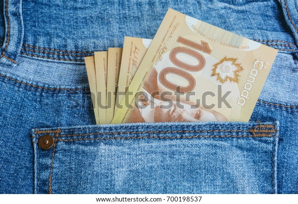 Canadian\
banknotes are in the back pocket of blue\
jeans.