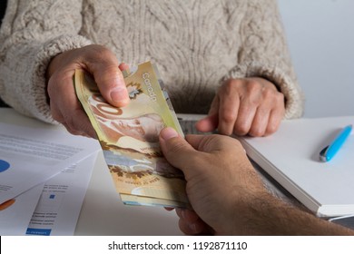 Canadian Currency. Dollars. Money From Canada. Old Person Delivering Large Amount Of Bills To Unknown Male.