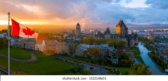 A Canadian flag flies over Old Quebec City at sunset. Aerial drone panorama view of Quebec City including Chateau Frontenac and Differin Terrace.