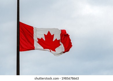 A Canadian Flag At Half Mast, Lowered In Remembrance Of The Indigenous Children Who Were Abused And Dies In Residential Schools. Overcast, Close View.