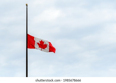 A Canadian Flag At Half Mast, Lowered In Remembrance Of The Indigenous Children Who Were Abused And Died In Residential Schools. Overcast, Wide View.