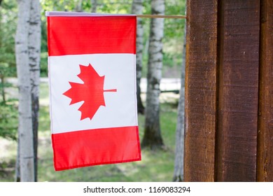 Canadian Flag Hanging On A Cabin Wall Exterior