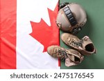 Canadian flag, military boots and helmet on green background