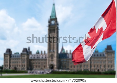 Canadian flag waving with Parliament Buildings hill in the background Ottawa,Ontario, Canada 
