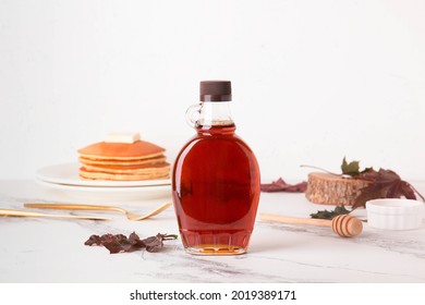 Canadian maple syrup in a bottle on a light background. Pancakes with syrup.