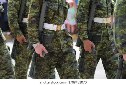 Canadian Military In Uniform And Army Fatigues Marching With Guns In A Parade On The Street